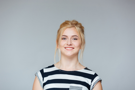 Portrait of cheeful pretty young woman in striped t-shirt over white backgroundの写真素材