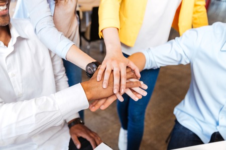 Closeup of multiethnic group of young people standing and joining hands