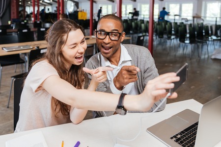 Cheerful funny young business people working and taking selfie in officeの写真素材
