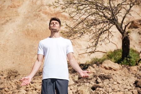 Relaxed handsome young man standing and meditating outdoorsの写真素材