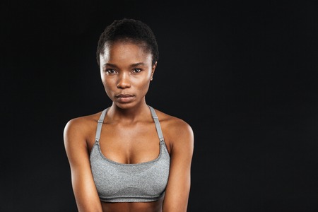 Beauty portrait of afro american fitness woman with perfect skin looking at camera isolated on a black backgroundの写真素材