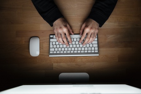 Top view of hands of young man typing on keyboardの写真素材