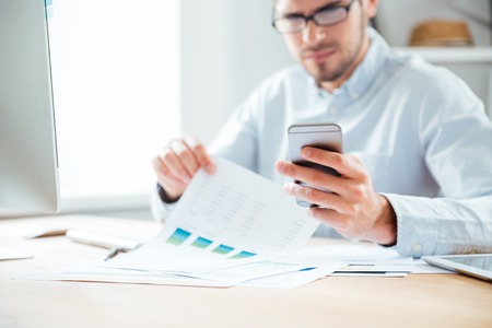 Cropped image of a happy young businessman using mobile phone while working in the officeの写真素材