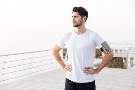 Portrait of confident young sportsman with mobile phone in armband