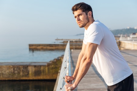 Portrait of thoughtful man athlete standing in pier in the morningの写真素材