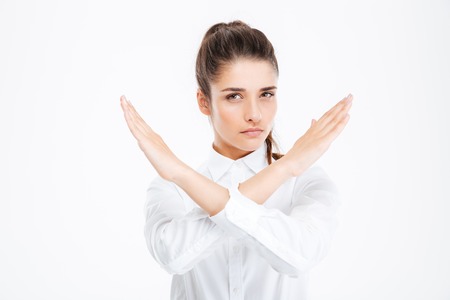 Beautiful young businesswoman with crossed hands showing stop gesture over white backgroundの写真素材
