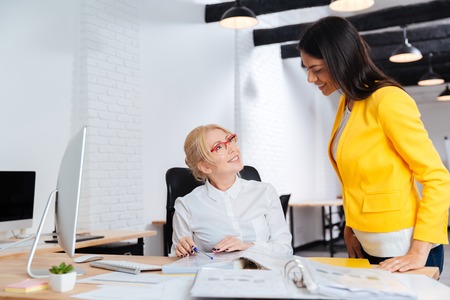 Two businesswomen talking and smiling while reviewing a work planの写真素材