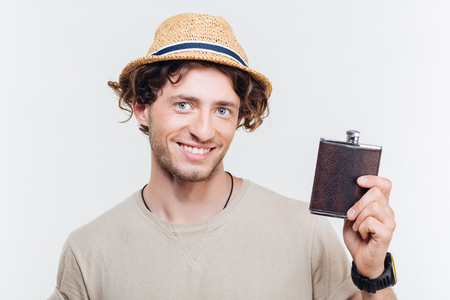 Close-up portrait of a happy young man holding alcohol flask isolated on the white backgroundの写真素材