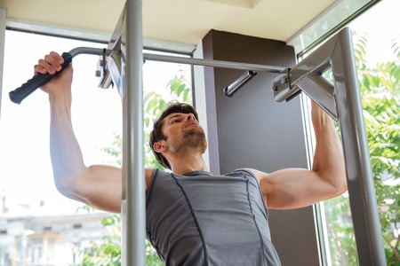 Attractive young sportsman doing exercises and training in gym