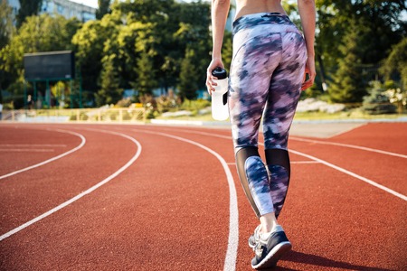 Cropped image of a fitness woman holding water bottle at the stadiumの写真素材