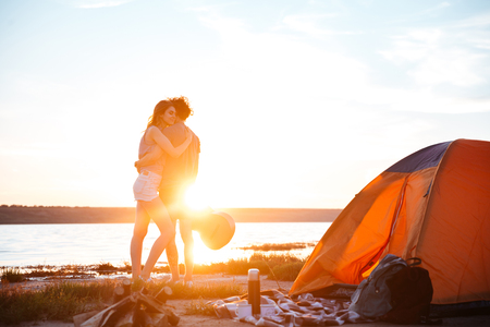 Portrait of a happy young couple hugging and standing at the seasideの写真素材
