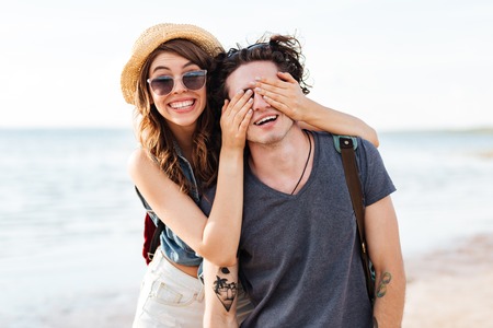 Cheerful young couple standing and having fun on the beach