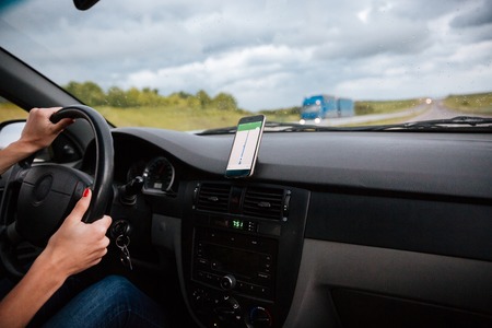Hands of woman driver on steering wheel of car driving on road in rainy weatherの写真素材