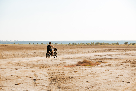 Man is kicking up dust as he rides his motorcycle through the desertの写真素材
