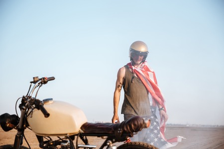 Close up of motorcycle with a man on the backgroud standing in desertの写真素材