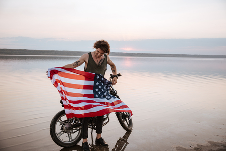 Man waving american flag at the desert standing near motorcycleの写真素材