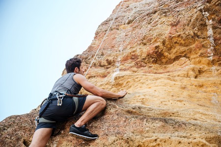 Young handsome sportsman climbing up a rock cliffの写真素材