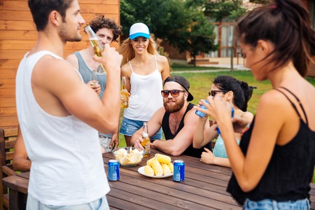 Group of happy young friends eating and drinking beer outdoorsの写真素材