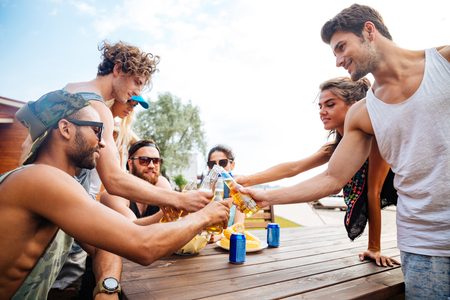 Group of happy young people with beer celebrating together outdoorsの写真素材