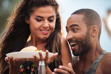 Surprised hungry young couple with fresh hamburger outdoorsの写真素材