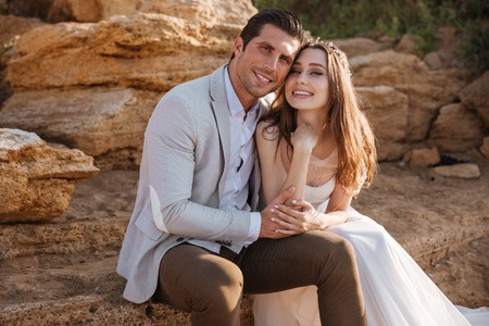 Romantic married couple sitting on the beach at sunsetの写真素材