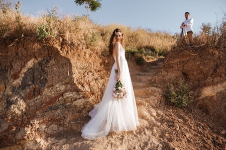 Just-married couple walking at the beach at sunsetの写真素材