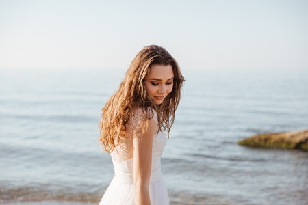 Young beautiful woman in wedding dress on beach having funの写真素材