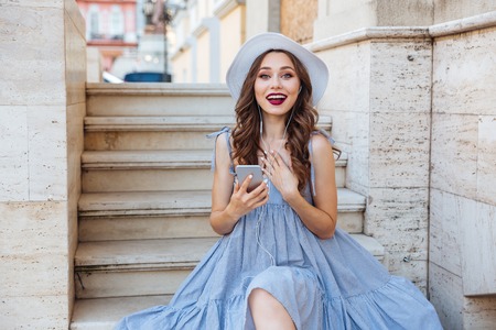 Young beautiful smiling woman in hat making selfie with smartphone outdoorsの写真素材