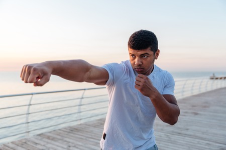 Focused african american young man athlete working out on pier in the morningの写真素材