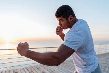 Athletic african american young sportsman boxing on pier in the morningの写真素材