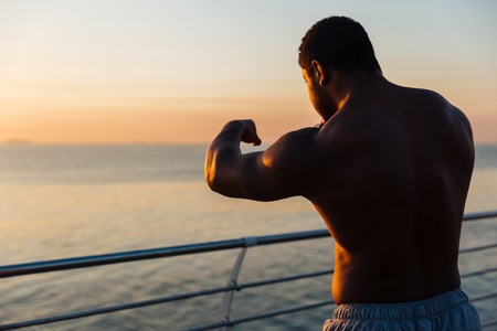 Silhouette of serious african american young man athlete boxing outdoors at sunrise