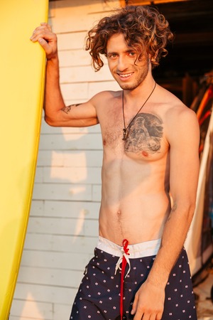 Close up portrait of a young curly surfer with surfboardの写真素材