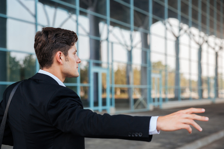Young brunette businessman stopping car with hand outdoorsの写真素材