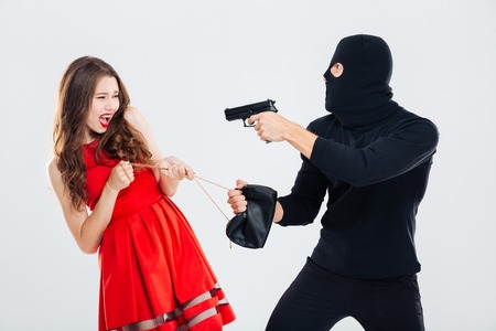 Man theif in balaclava threatening with gun and stealing young woman bag