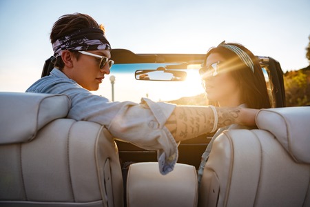 Portrait of beautiful young couple sitting in cabriolet in summerの写真素材