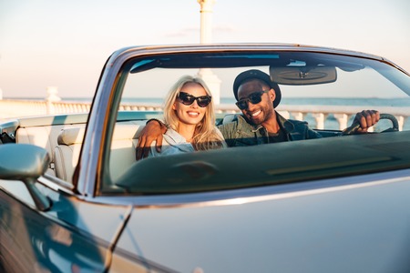 Happy young couple in sunglasses driving cadrioletの写真素材
