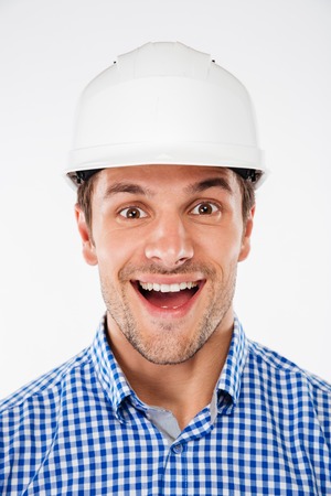 Portrait of cheerful excited young man architect in hard hatの写真素材