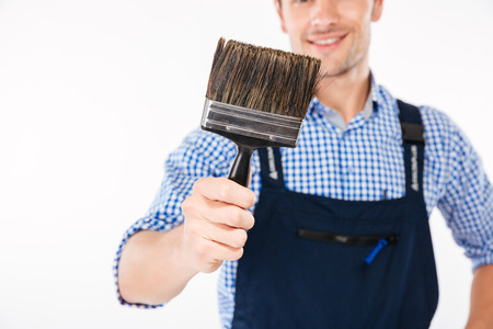 Cropped image of smiling male builder holding paint brush isolated on a white backgroundの写真素材
