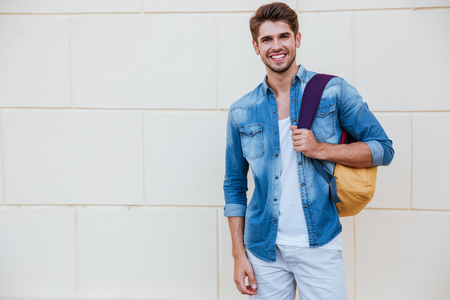 Portrait of cheerful young man with backpack standing and smilingの写真素材