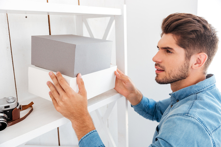 Hanadsome young man putting boxes on the shelf in officeの写真素材