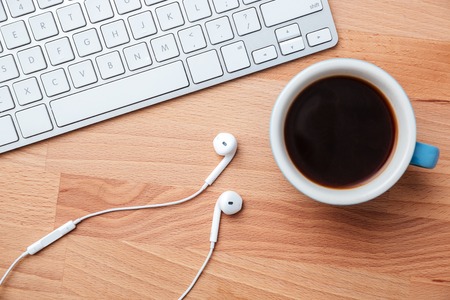 Top view coffee cup earphones and keyboard over wooden backgroundの写真素材