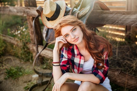 Attractive redhead young woman cowgirl sitting and relaxing outdoorsの写真素材