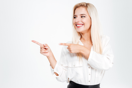 Happy young businesswoman pointing fingers away at copyspace isolated on white backgroundの写真素材