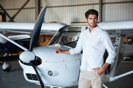 Portrait of attractive young man standing near small aircraftの写真素材
