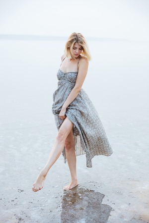 Beautiful young woman walking barefoot in lakeの写真素材