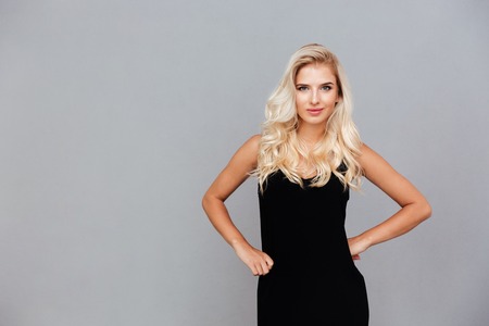 Beautiful young woman in black dress posing isolated on a gray backgroundの写真素材