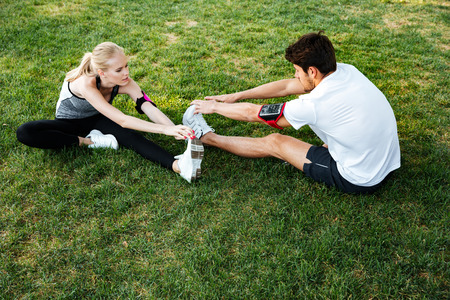 Young couple exercising and stretching muscles before sport activity outdoors