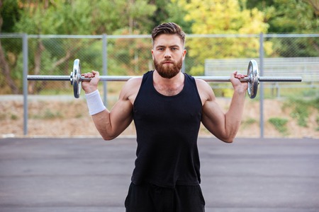 Muscular bearded fitness handsome man workout with barbell outdoorsの写真素材
