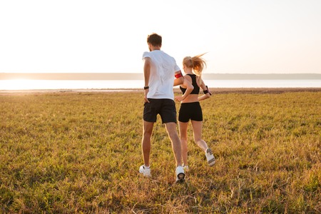 Back view of young fitness man and woman doing jogging sport outdoorsの写真素材