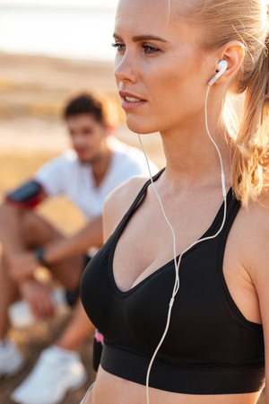 Beautiful young blonde sports woman with earphones outdoorsの写真素材